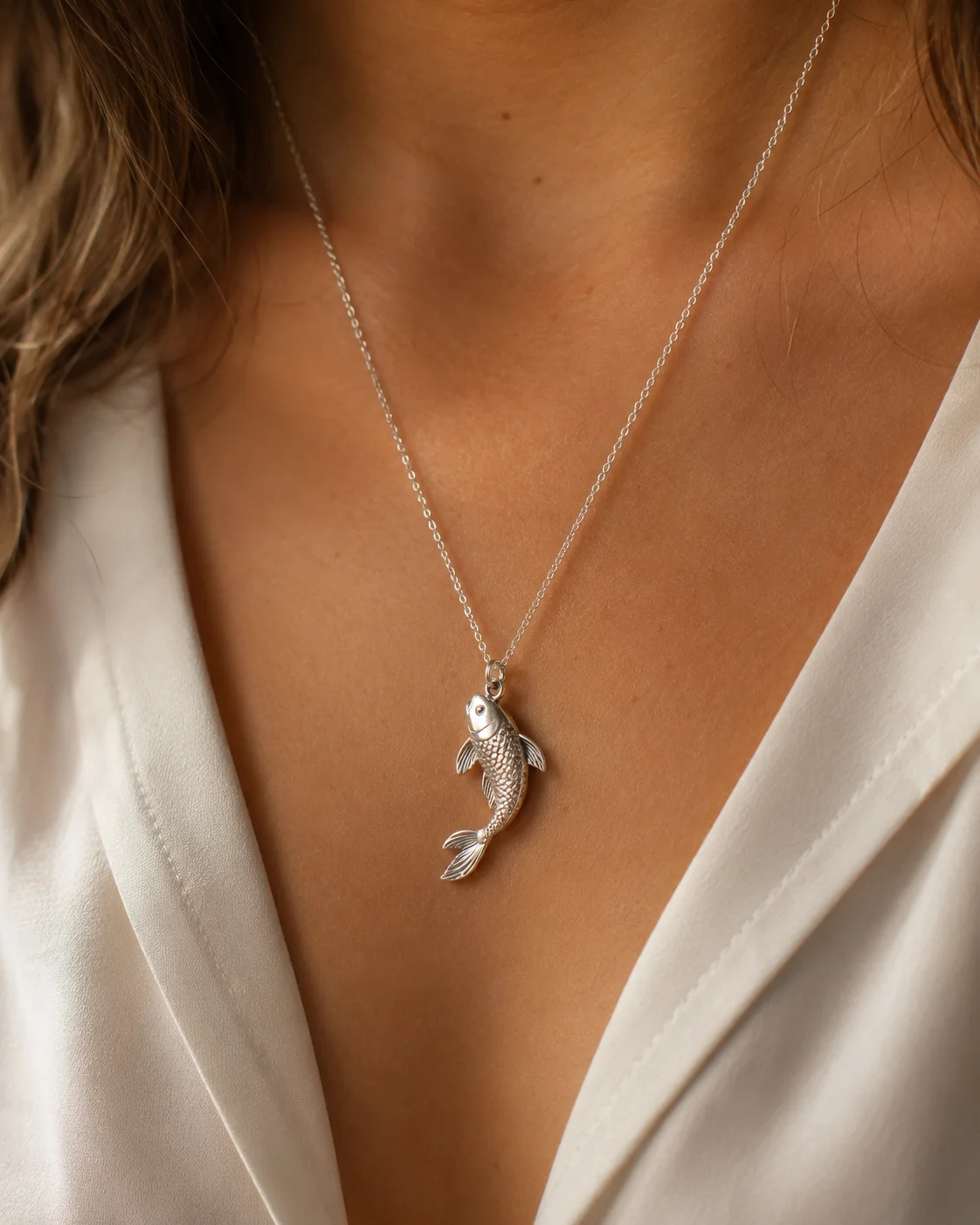 Woman wearing a silver koi fish pendant necklace โ fish pendant benefits for luck, wealth, and spiritual protection